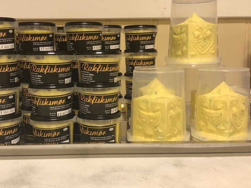 Stablede bokser med rakfisksmør og vakkert dekorerte, store kuber smør i gjenneomsiktige, runde bokser.